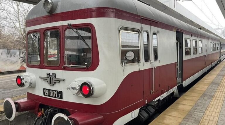 Decorated vintage BDZ railcar departs Sofia station carrying passengers celebrating Baba Marta spring tradition excursion